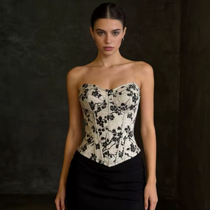 Model wearing a strapless, structured Ivy bustier corset with a cream and black floral print and sweetheart neckline.