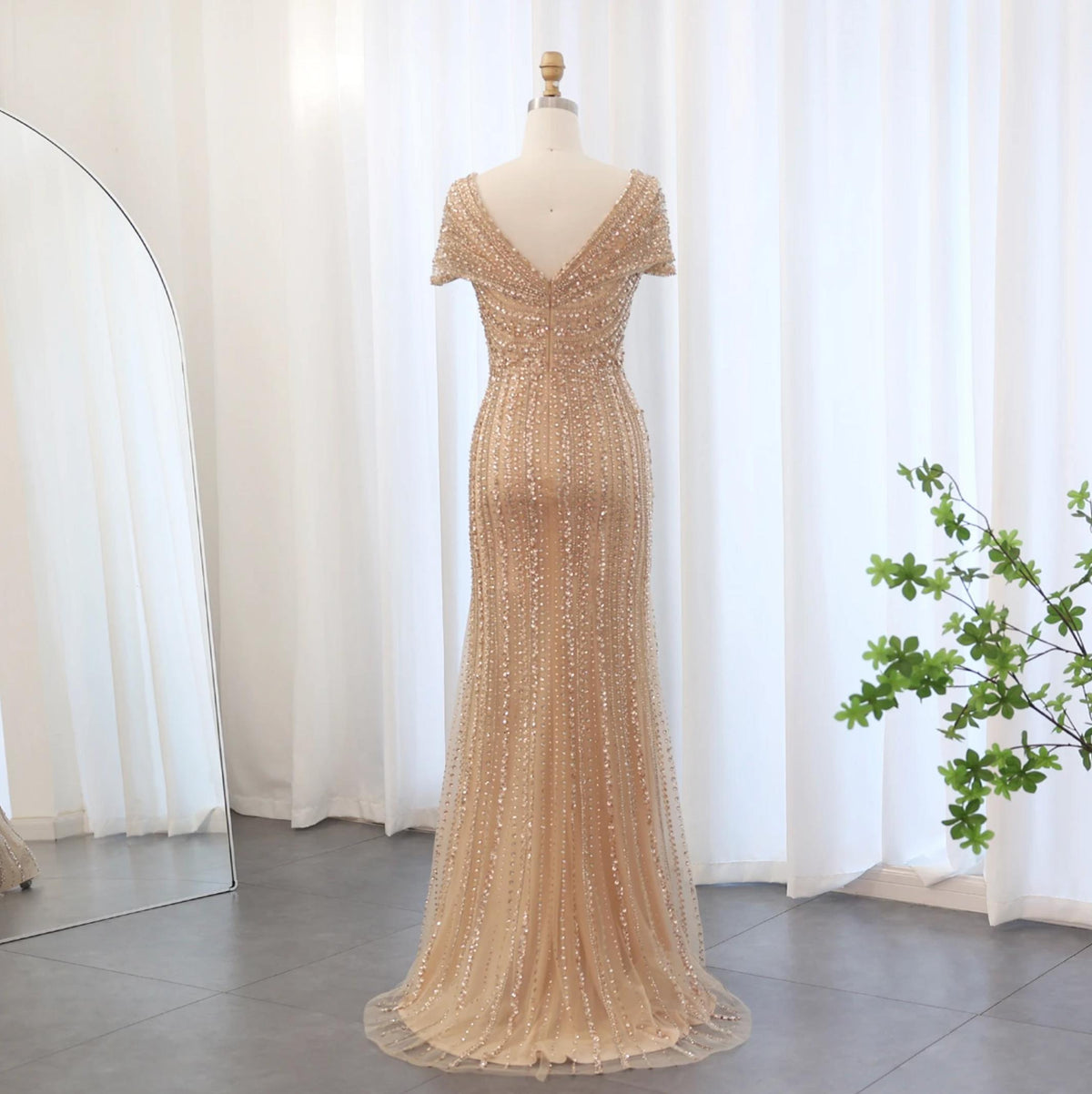Silver nude mermaid gown with intricate crystal and sequin beading, featuring a V-neck and elegant sweeping train.