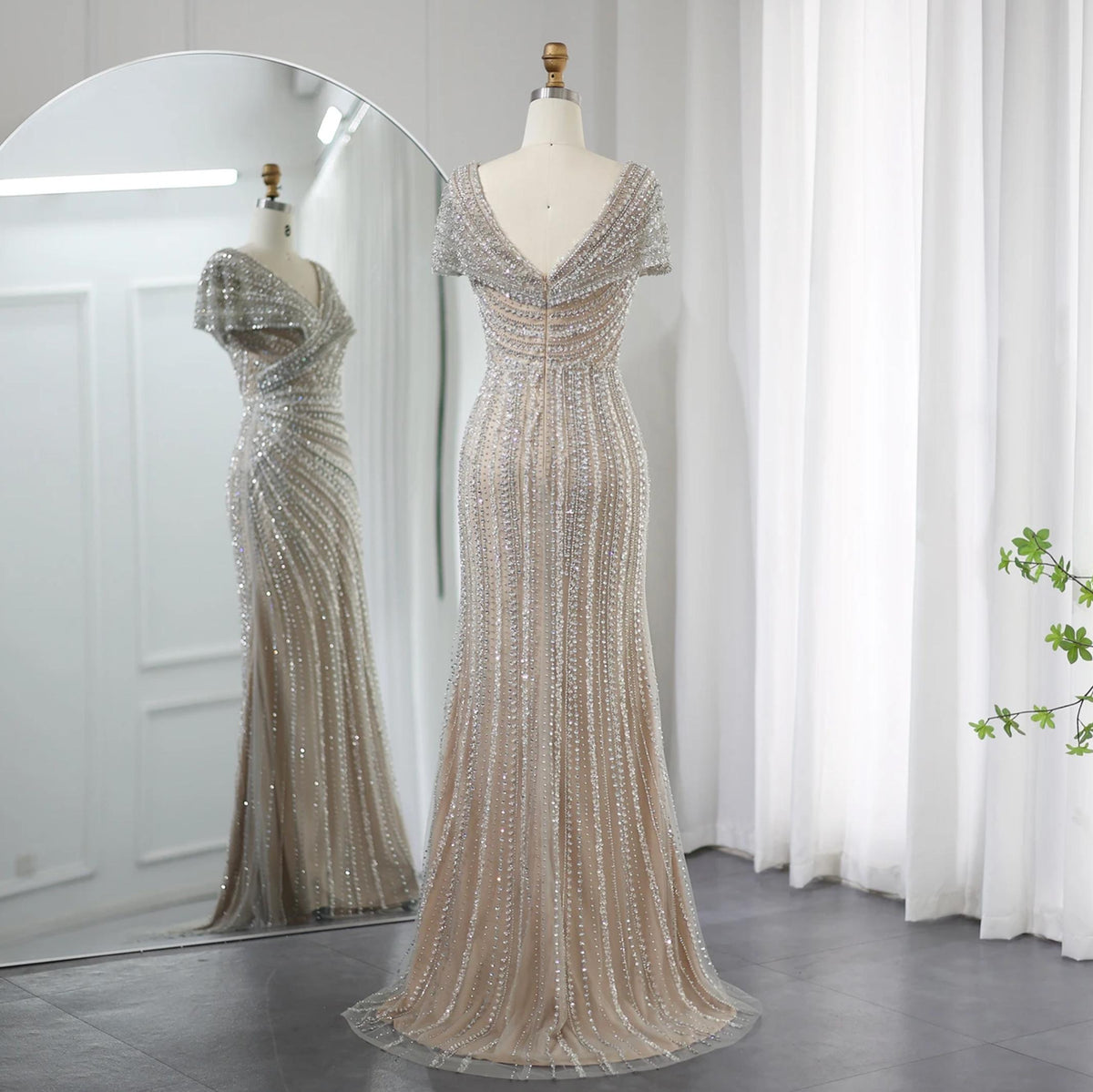 Silver nude mermaid gown with intricate crystal and sequin beading, V-neck, and short sleeves on a dress form.