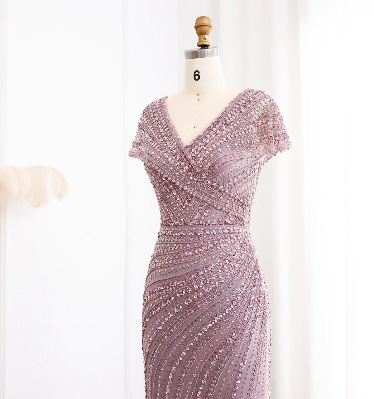 Silver nude mermaid gown with a V-neck, cap sleeves, and intricate crystal and sequin beadwork on a dress form.