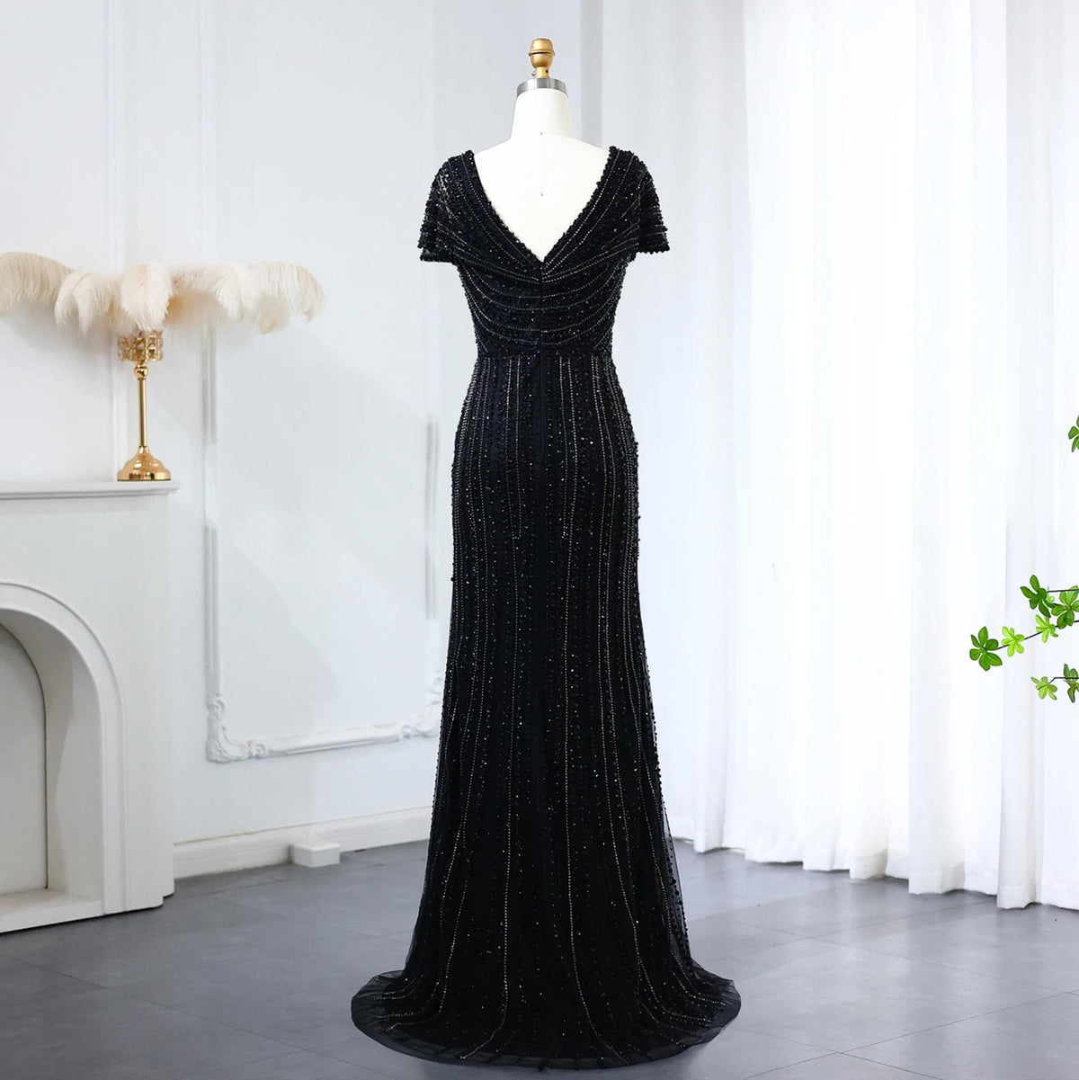 Black mermaid evening gown with short sleeves, V-neck, and intricate vertical beaded embellishments on a mannequin.