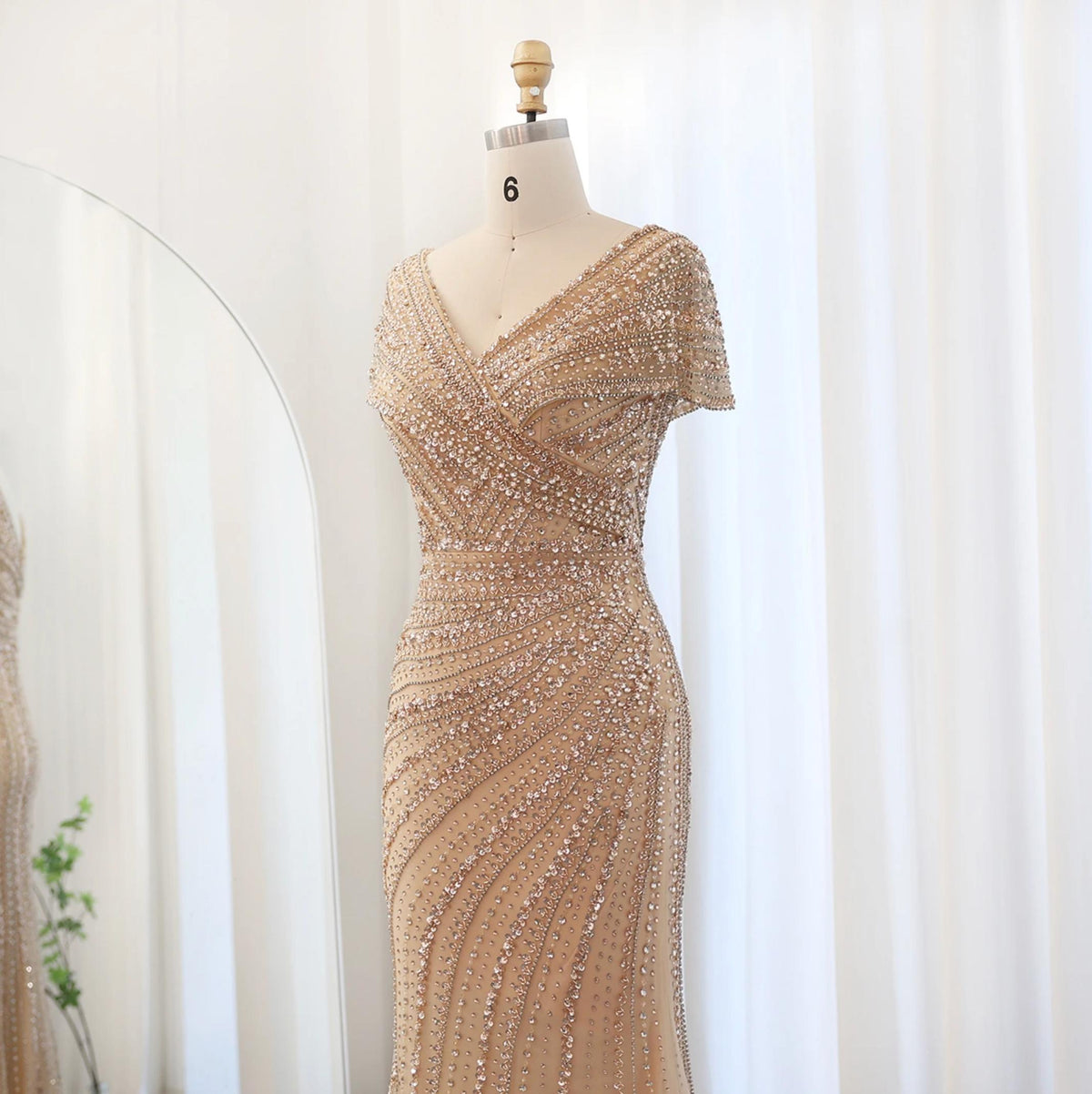Silver nude mermaid gown with a V-neck, intricate crystal and sequin beadwork on a mannequin.