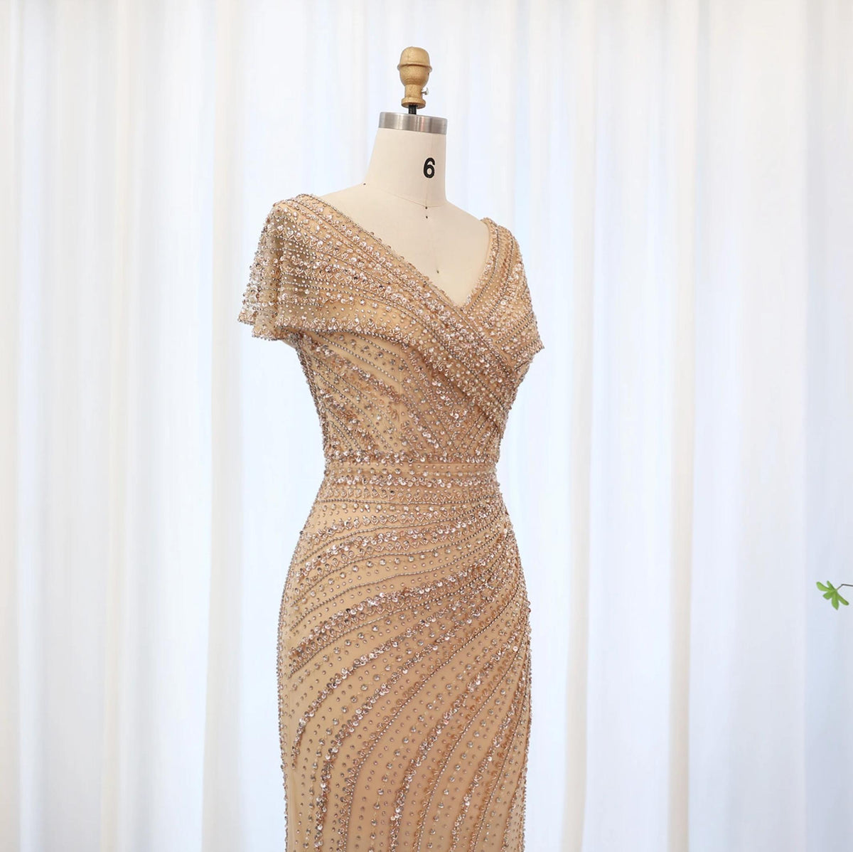 Silver nude mermaid gown with a plunging V-neck, intricate crystal and sequin beadwork on a mannequin.