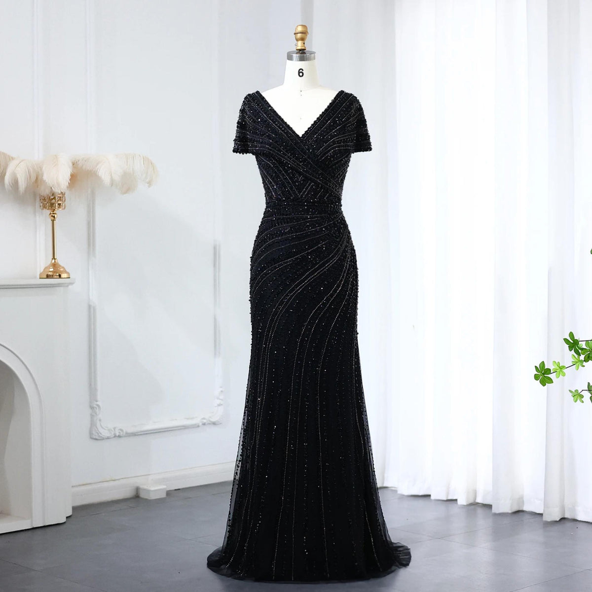 Black mermaid gown with V-neck, short sleeves, and intricate beaded crystal embellishments on a mannequin.