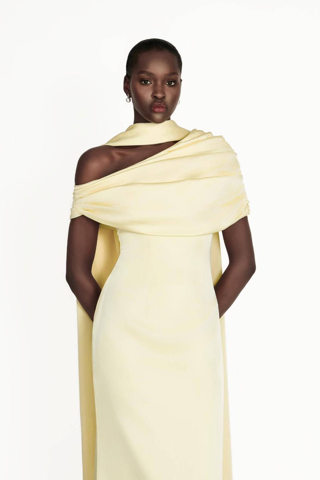 Model wearing a pale yellow satin Kulture dress with a gathered Bardot neckline and elegant A-line silhouette.