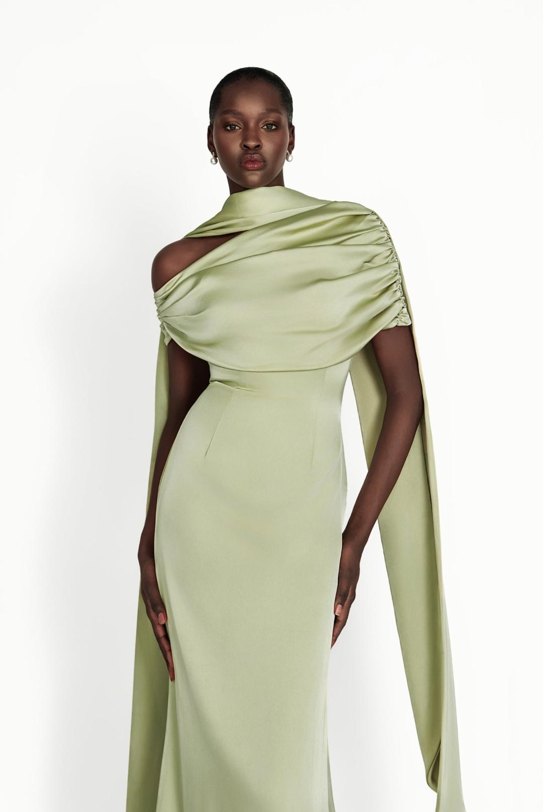 Sage green satin Kulture dress with a gathered Bardot neckline and flowing A-line silhouette on a model.