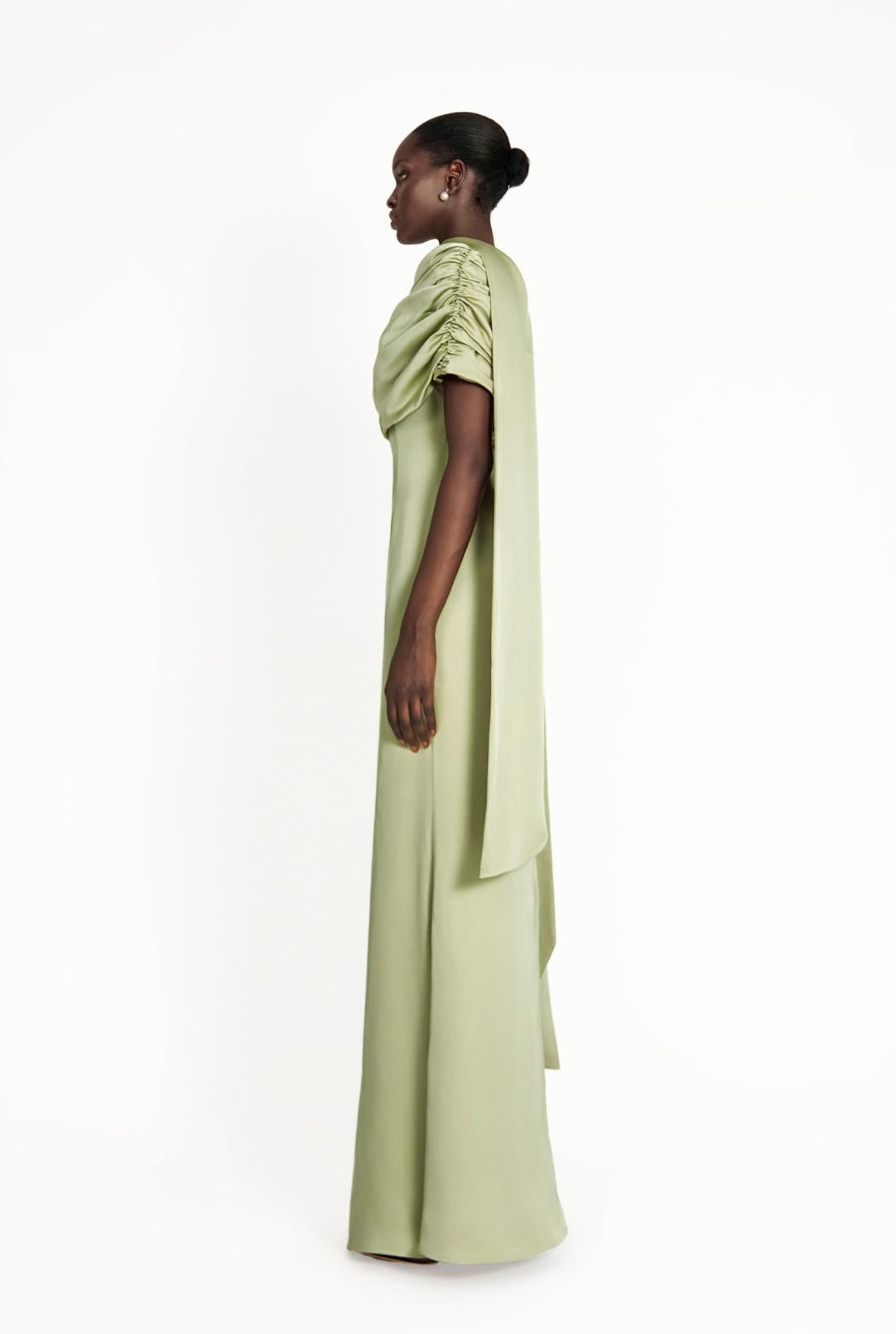 Sage green satin Kulture dress with a gathered Bardot neckline and flowing A-line silhouette on a model.