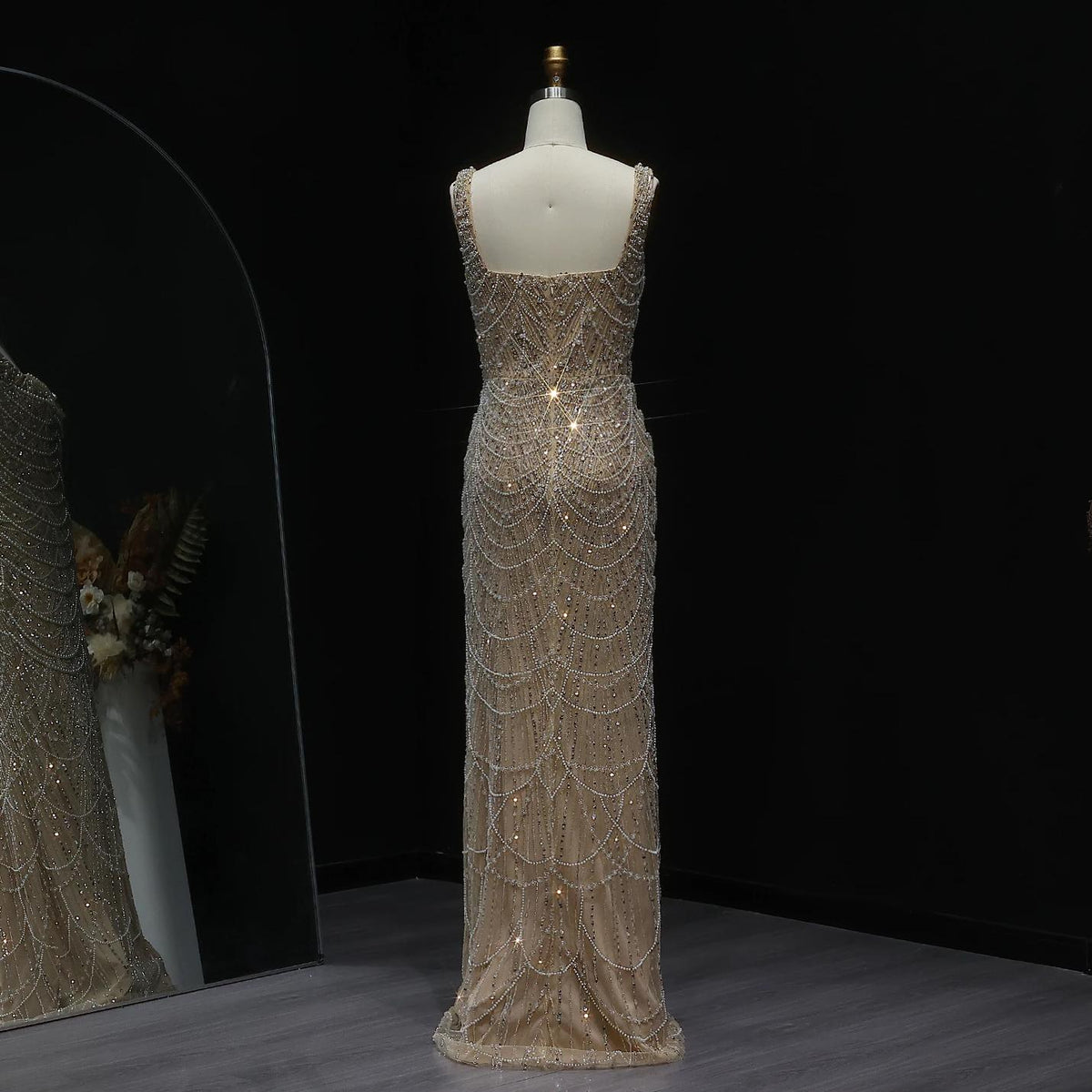Nude floor-length sheath gown with intricate pearl and bead embellishments, scoop neckline, and sleeveless silhouette.