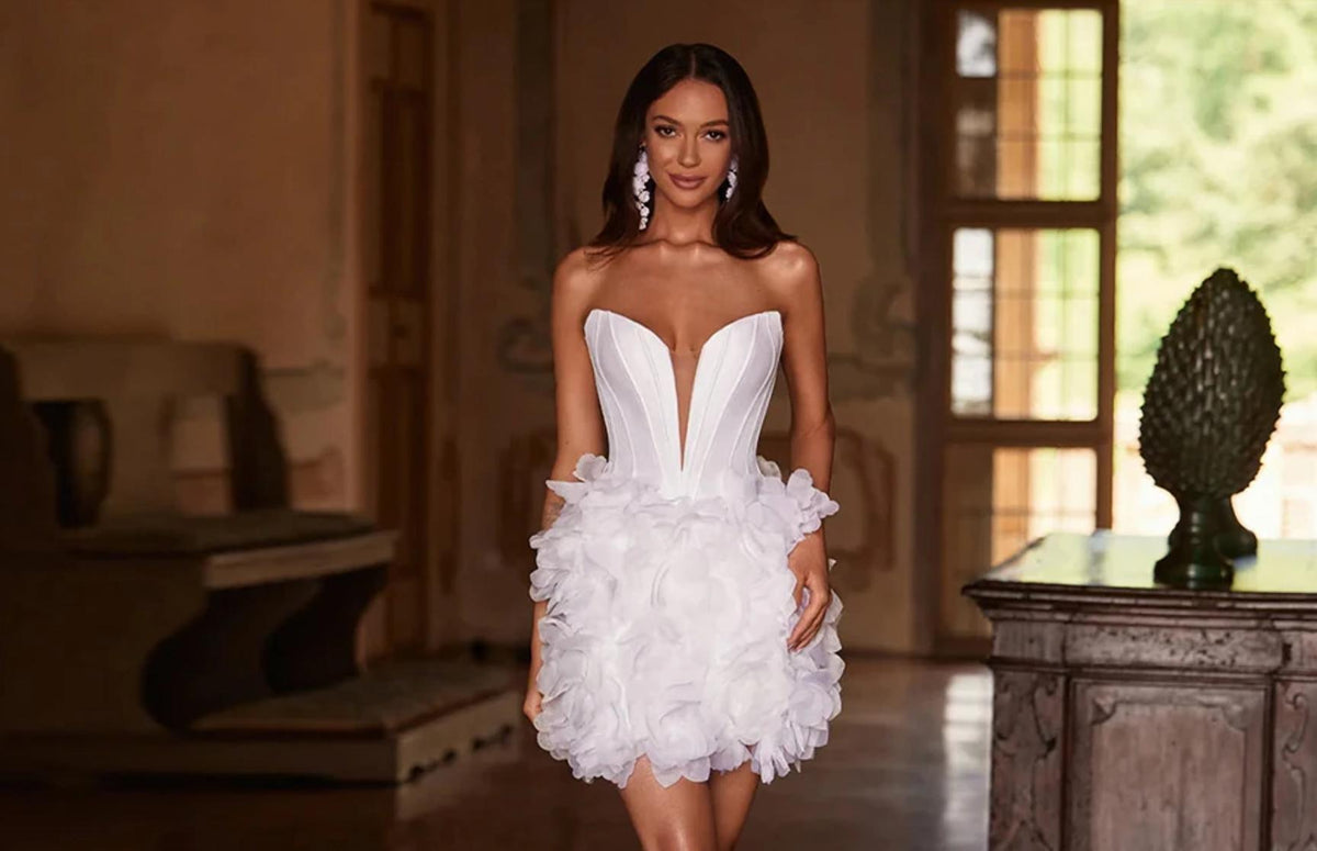 White mini party dress with a sweetheart neckline, structured bodice, and a voluminous tulle skirt featuring handmade floral details.
