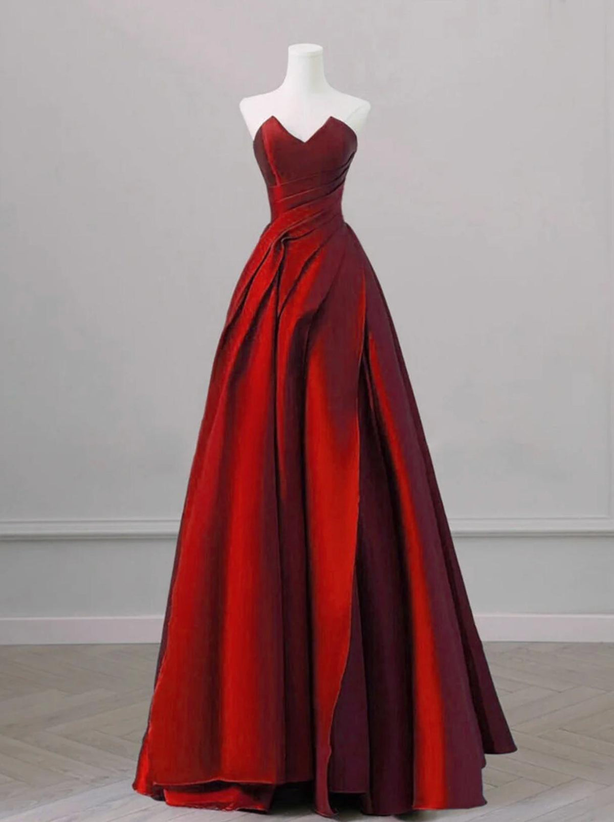 Elegant red satin A-line gown with a sweetheart neckline and draped bodice on a mannequin.