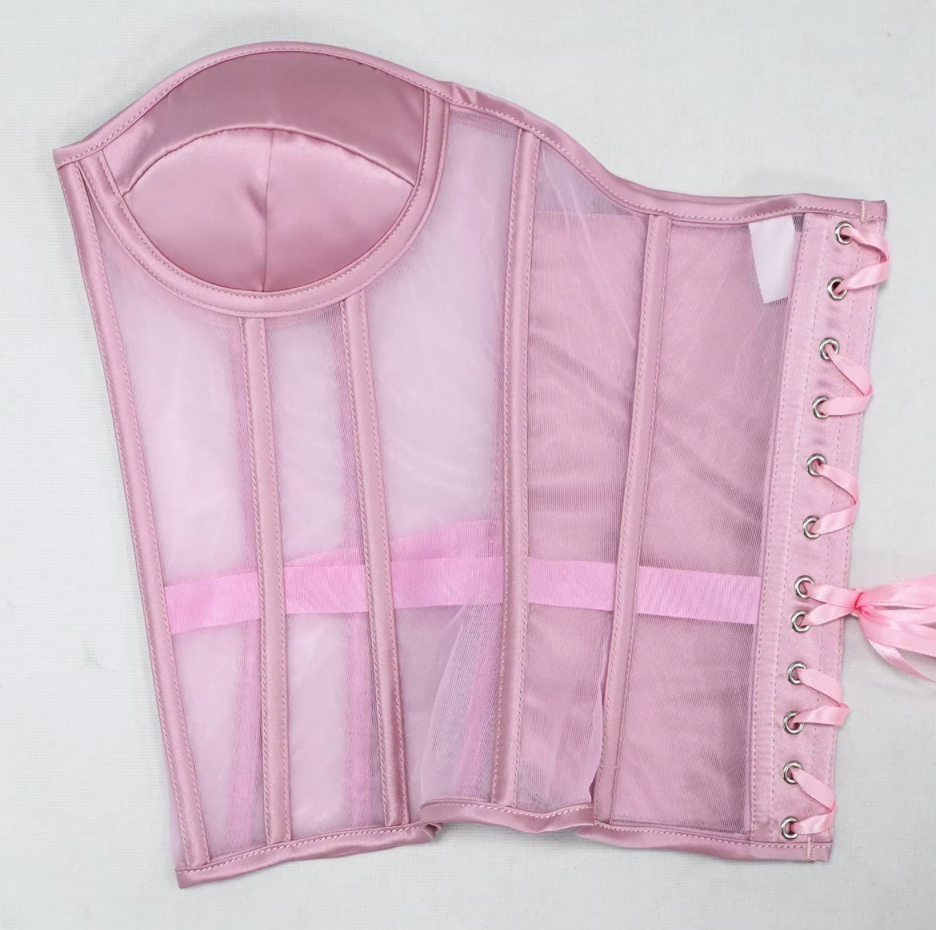The Lilah light pink structured corset bustier with sheer mesh panels, satin lining, a waist belt, and side lacing with metal eyelets.