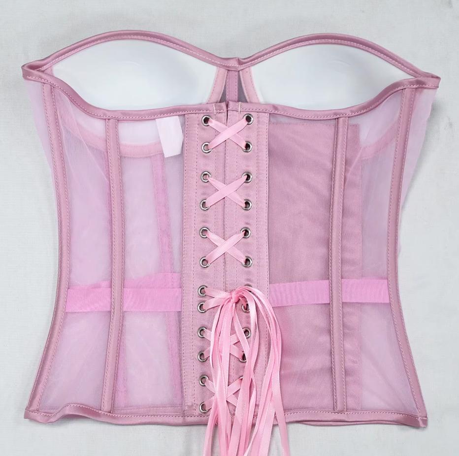 The Lilah light pink sheer mesh corset with a lace-up back closure, featuring multiple adjustable laces, silver metal eyelets, and a matching pink waistband, laid flat against a white background.