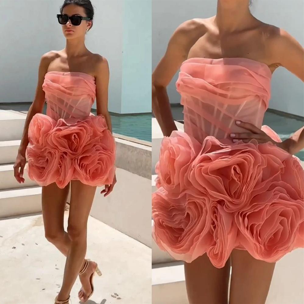 Coral pink strapless mini dress featuring a structured corset bodice and voluminous 3D organza flower skirt.