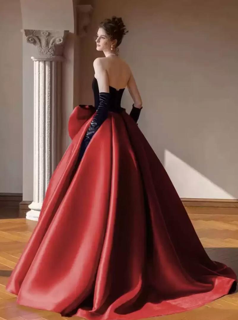 Strapless two-tone satin A-line gown with a sweetheart neckline, oversized back bow, and floor-length red skirt.