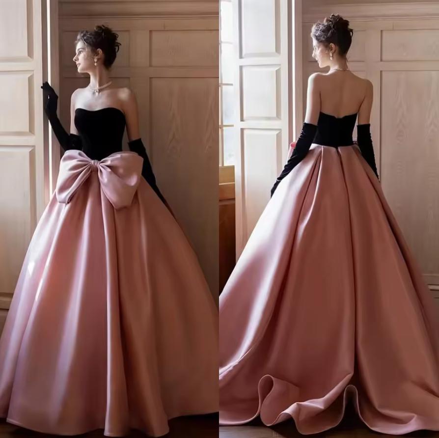 Strapless two-tone satin A-line gown with a black bodice, pink floor-length skirt, and an oversized bow detail.