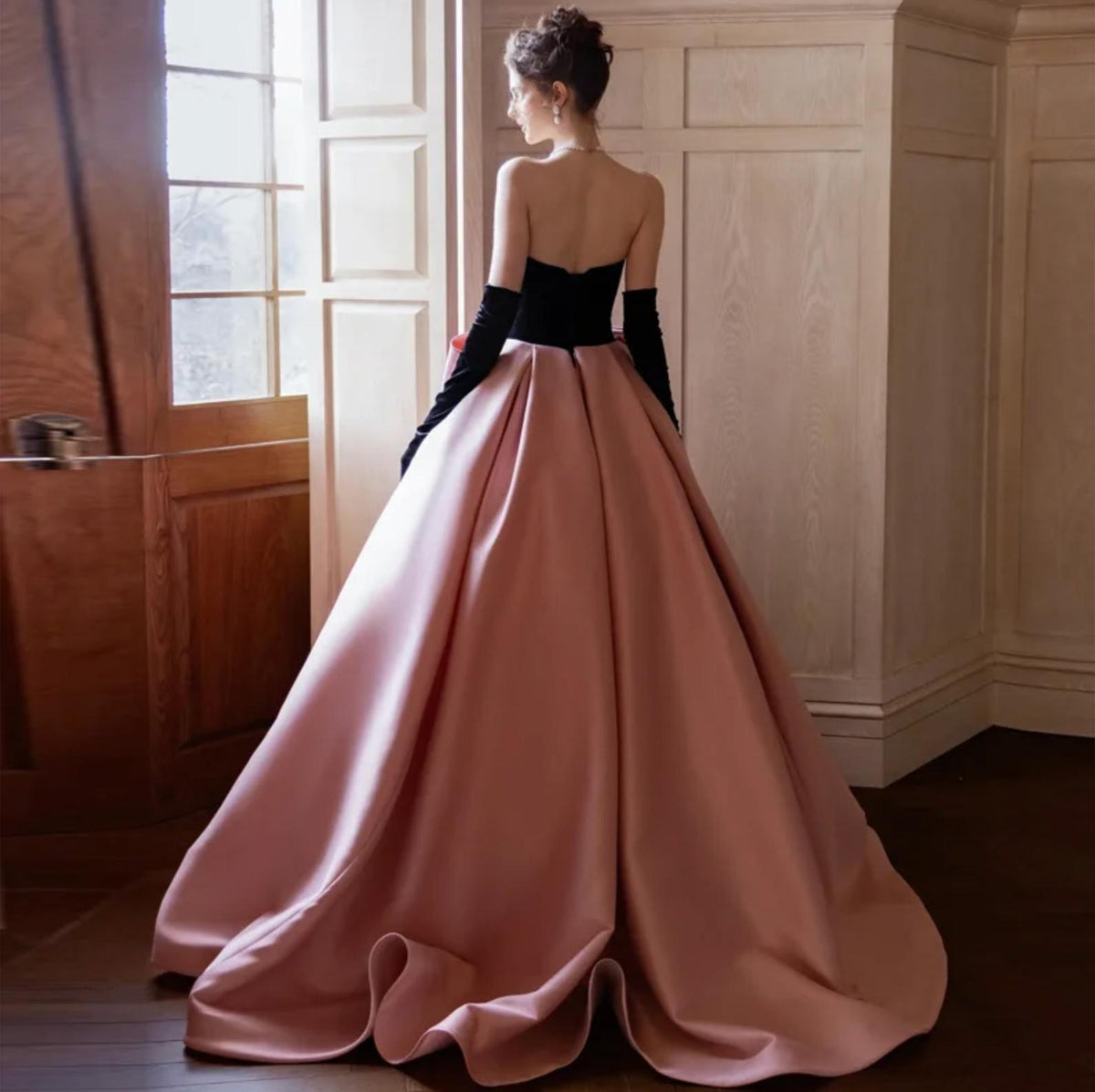 Strapless two-tone satin A-line gown with a black bodice, pink floor-length skirt, and oversized back bow detail.