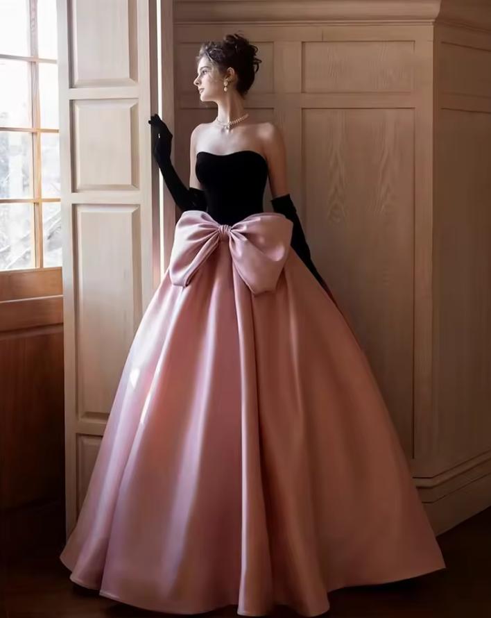 Strapless two-tone satin A-line gown with a black bodice, pink floor-length skirt, and oversized bow detail.
