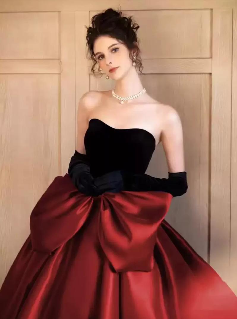 Strapless two-tone satin A-line gown with a sweetheart neckline and a large red bow at the waist.