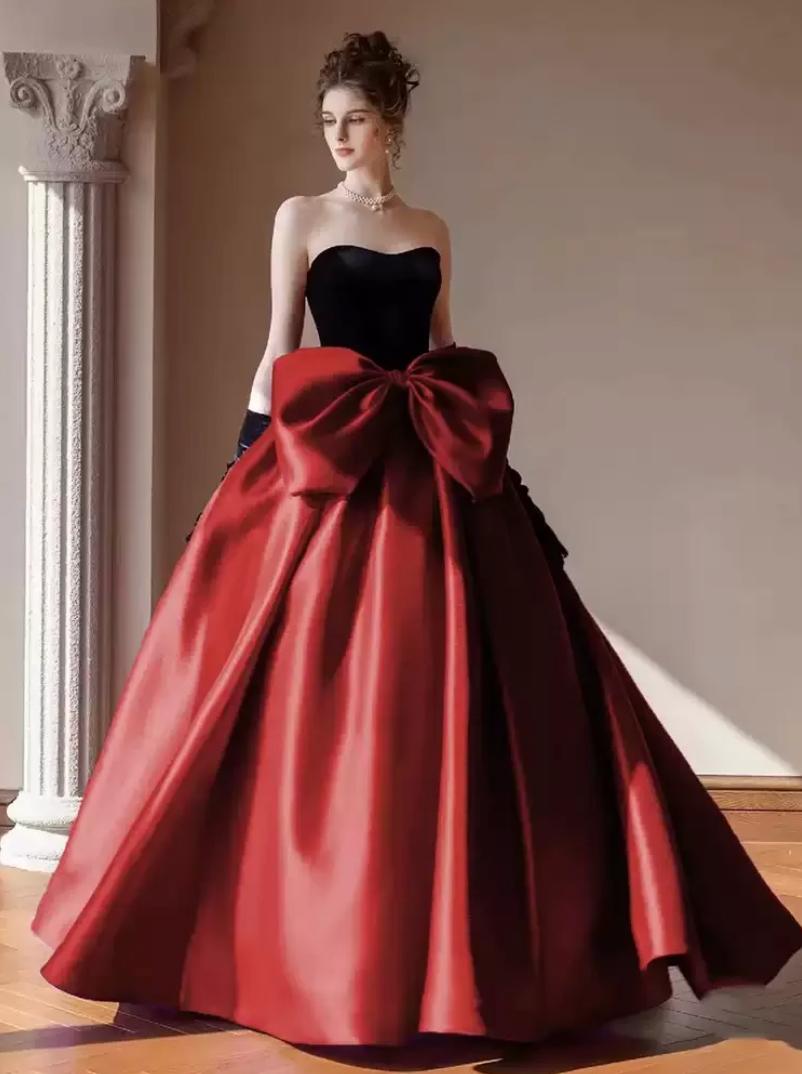 Strapless two-tone satin gown with a black sweetheart bodice, red A-line skirt, and an oversized bow at the waist.