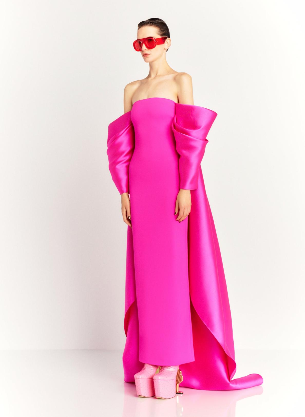 Model in a strapless hot pink satin evening gown with dramatic puff sleeves and a long court train.