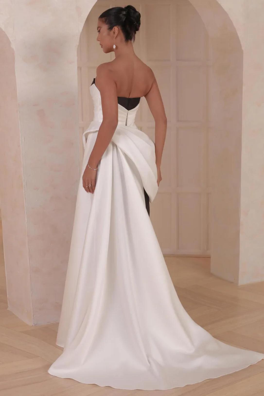 Strapless black and white A-line wedding gown with a pleated skirt and sweeping train in a formal bridal setting.