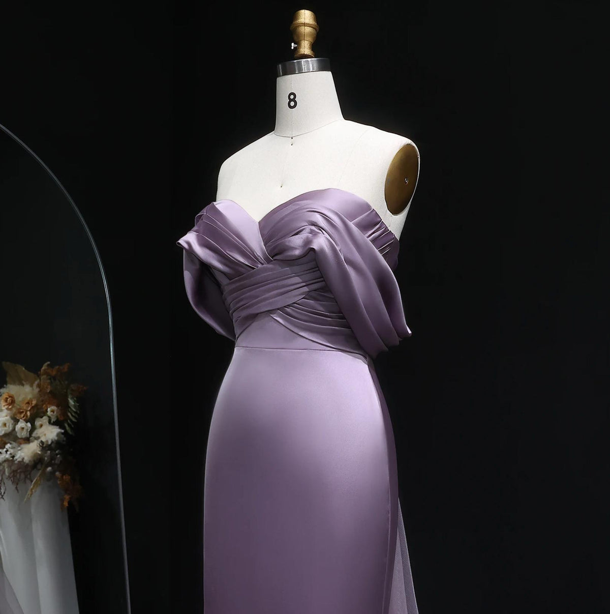 Lavender satin mermaid evening gown with an elegant off-shoulder neckline and delicate bodice pleating on a mannequin.