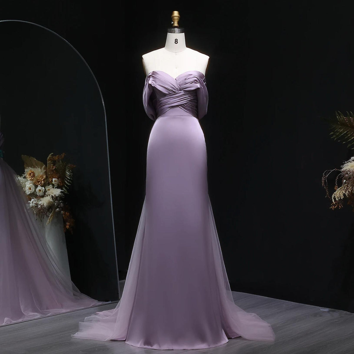 Elegant lavender satin mermaid evening gown with off-shoulder pleated bodice and tulle train on a mannequin.