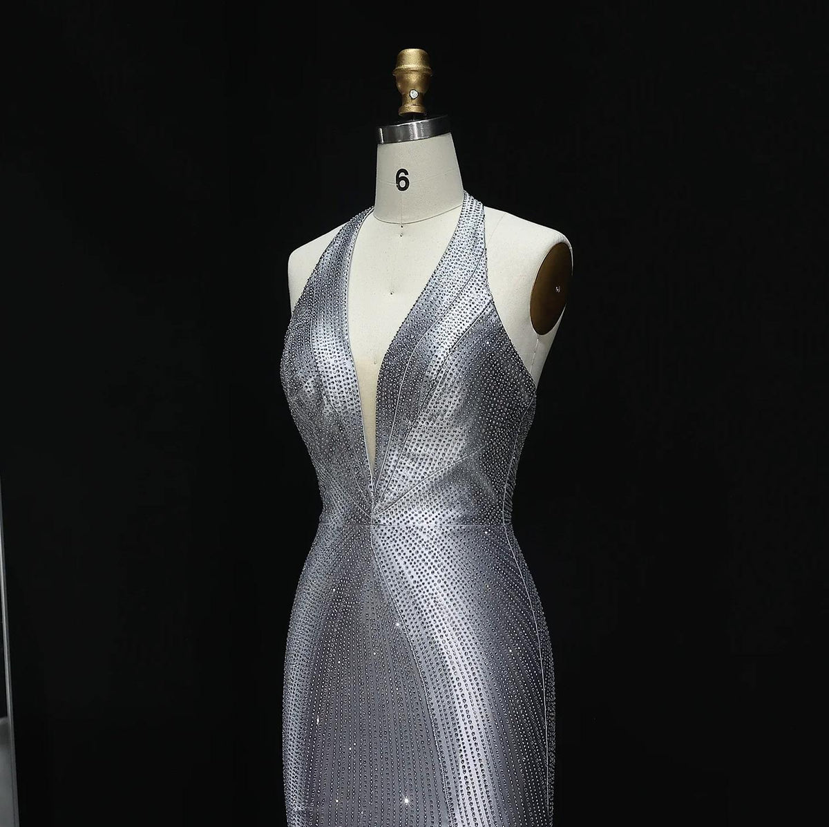 Midnight Soiree silver satin halter gown featuring a deep V-neckline and intricate crystal embellishments on a mannequin.