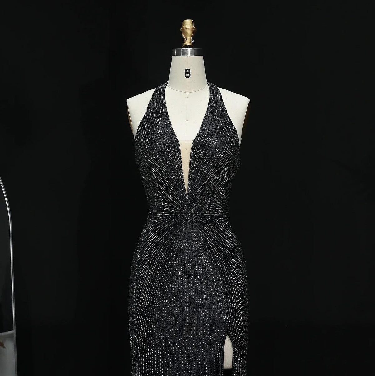 Midnight Soiree black satin evening gown with crystal appliqués, halter neckline, and a thigh-high slit on a mannequin.