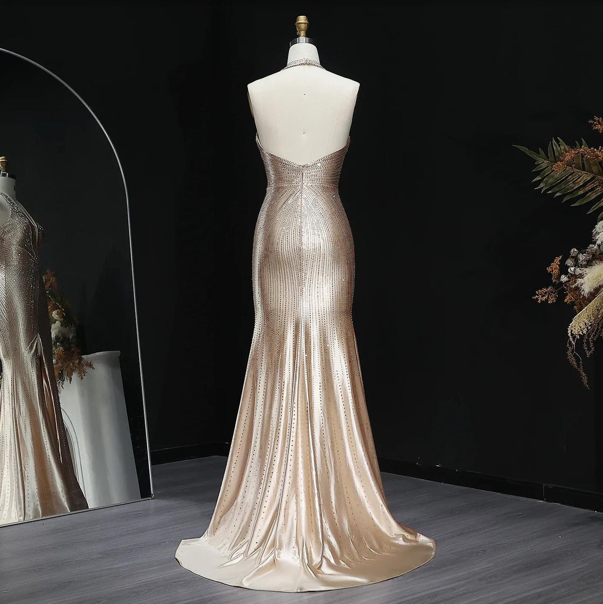 Backless champagne satin evening gown with crystal embellishments, halter neckline, and a sweeping floor-length train.