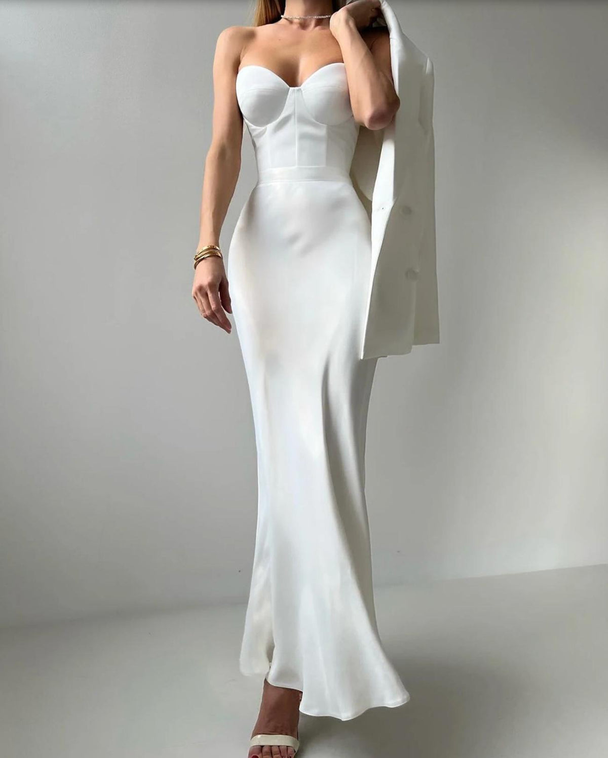 White two-piece set featuring a strapless corset-style bodice, floor-length mermaid skirt, and matching blazer.