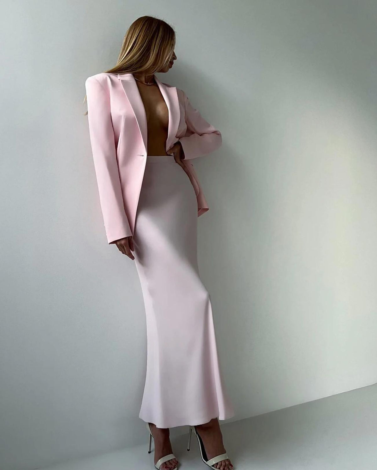 Woman wearing a pale pink two-piece set with a single-button blazer and a floor-length mermaid skirt.