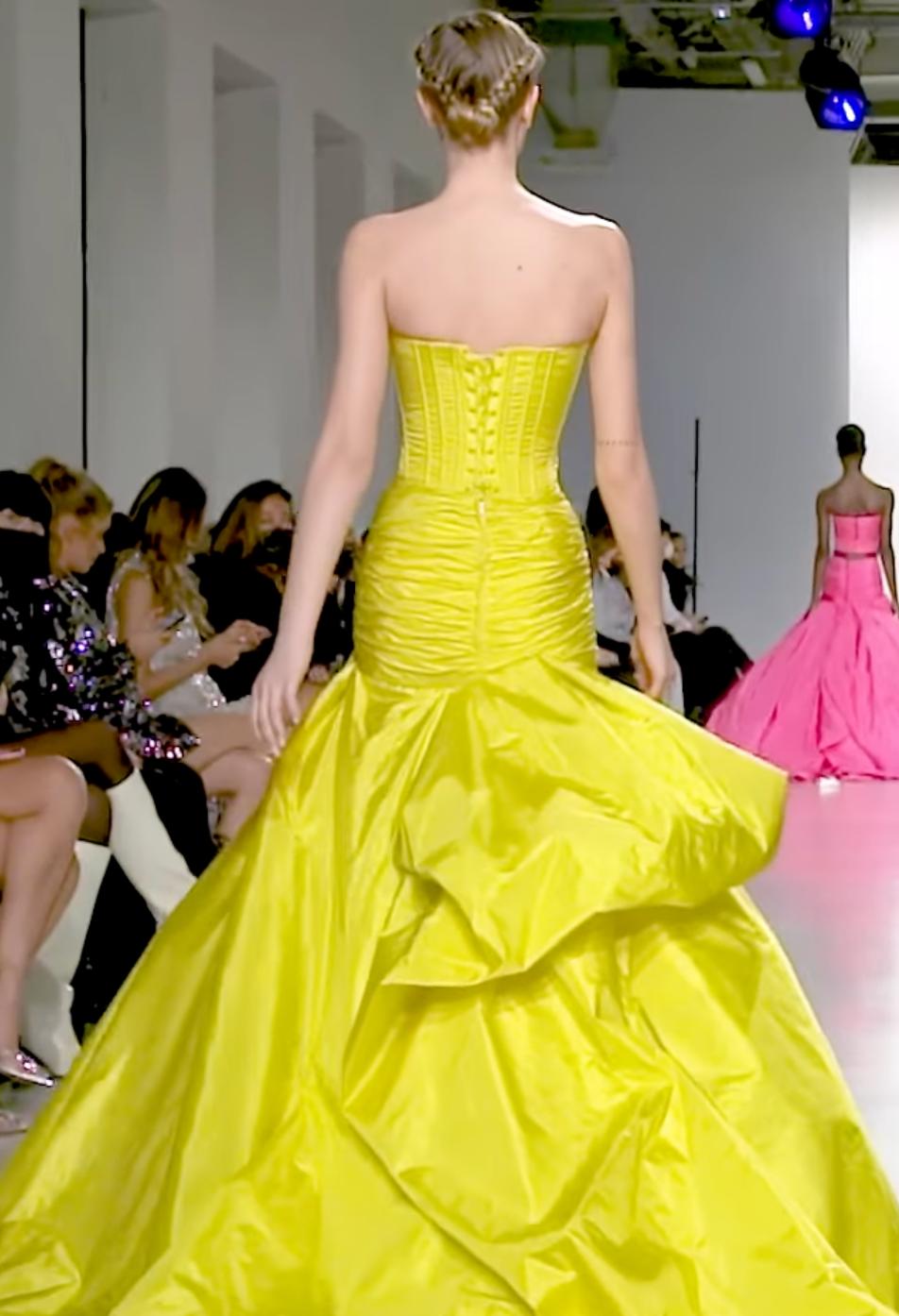 Yellow strapless taffeta formal gown with a corset back, pleated bodice, and dramatic floor-length sweep train.