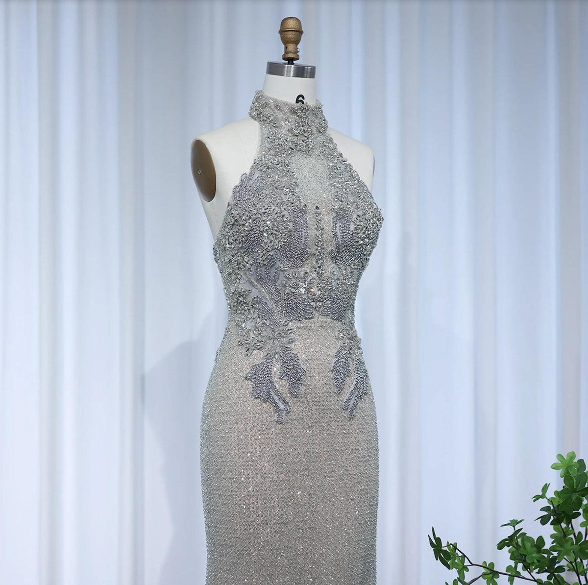 Silver floor-length A-line gown with a beaded halter neckline, intricate crystal embellishments, and soft tulle fabric.