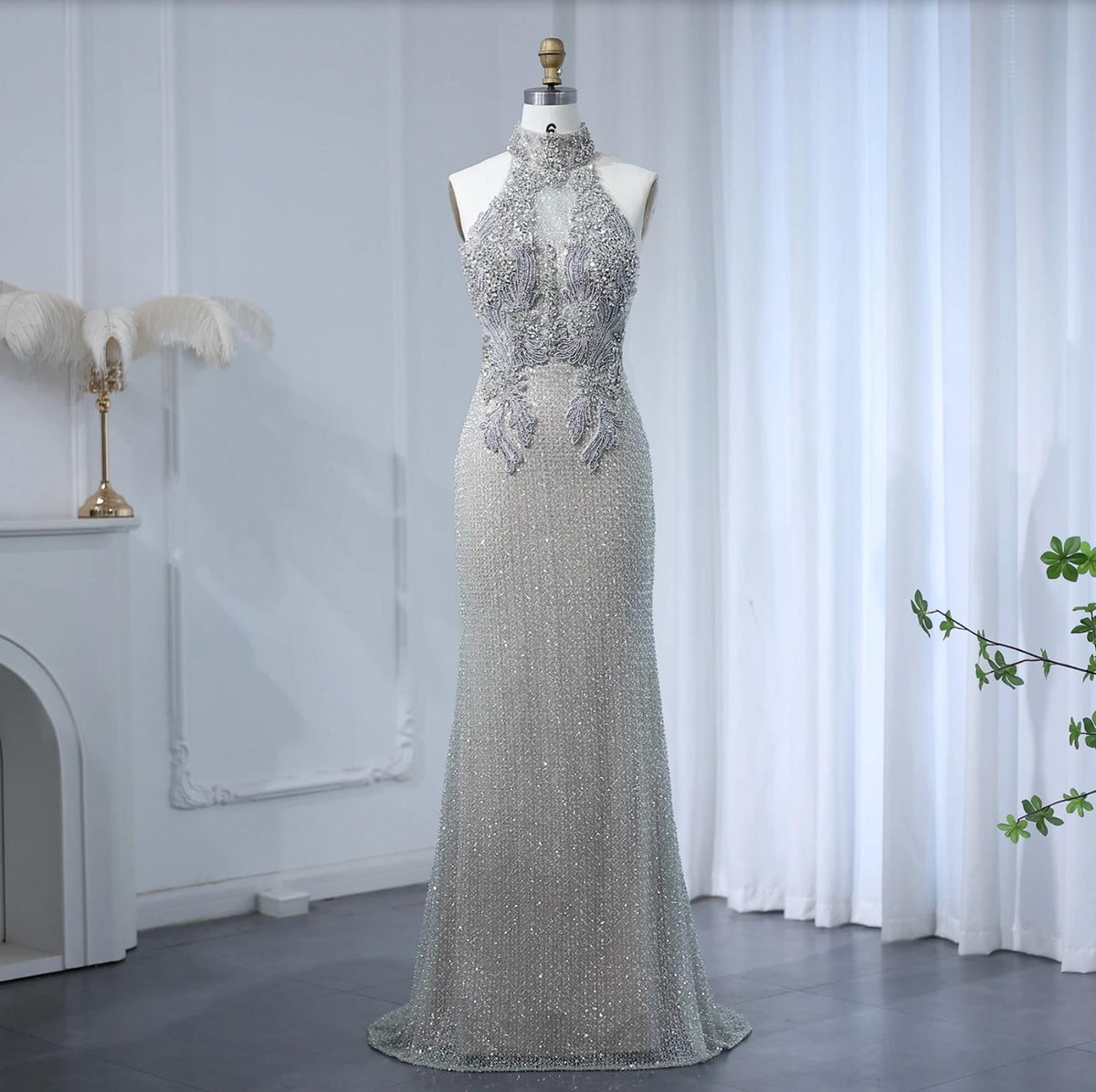 Floor-length silver A-line gown with a beaded halter neckline, intricate crystal embellishments, and sheer tulle details.