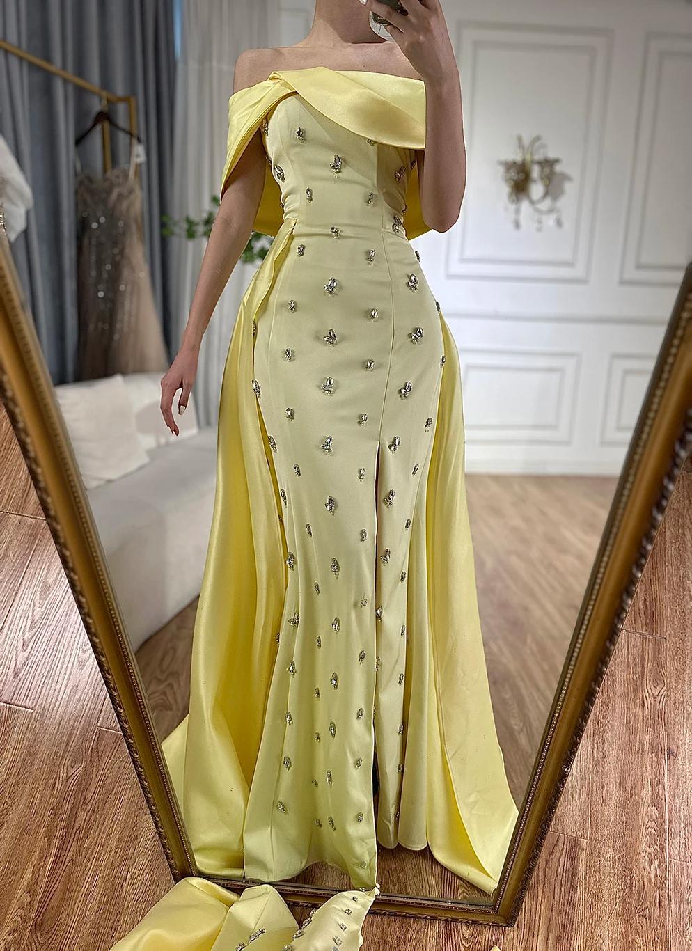 Yellow satin off-shoulder Mulholland gown with a crystal-beaded overskirt and elegant A-line silhouette.