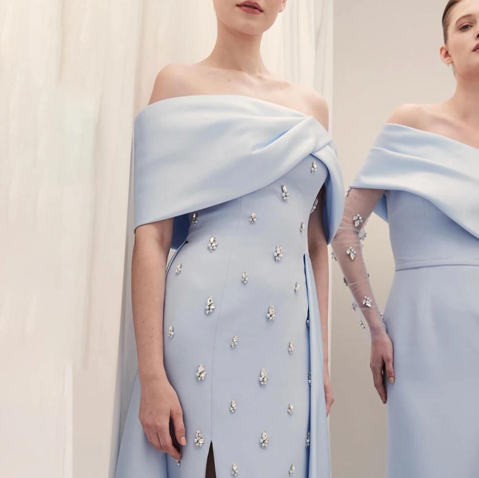 Light blue off-shoulder satin gown featuring a crystal-beaded overskirt and elegant A-line silhouette.