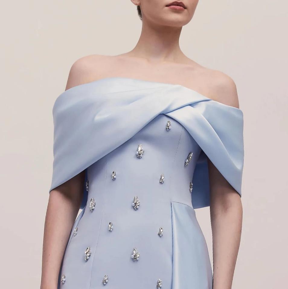 Light blue off-shoulder satin gown featuring a draped neckline and scattered crystal embellishments.