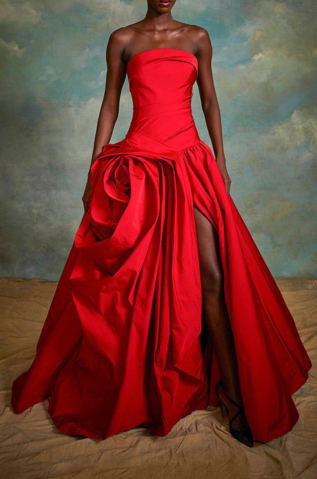 Red strapless gown with a hand-draped rose detail and side slit, crafted from luxurious crepe fabric.
