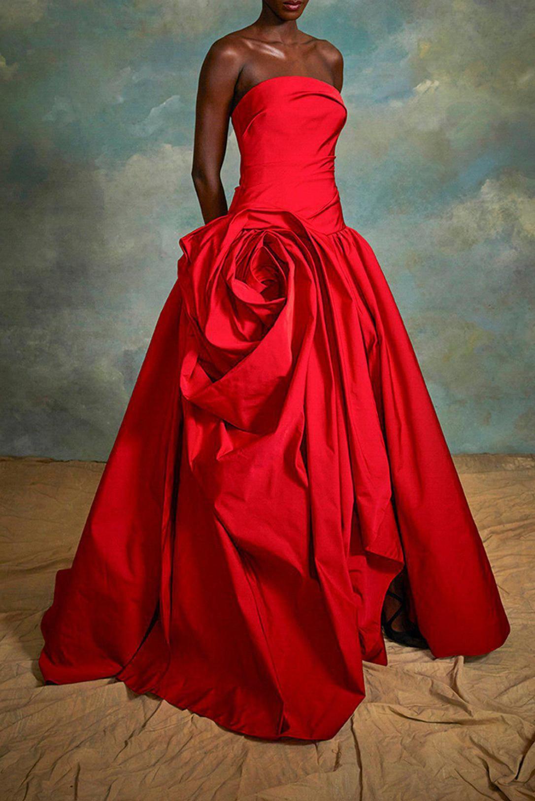 Red strapless gown in luxurious fabric featuring an exquisite hand-draped rose detail and a subtle side slit.