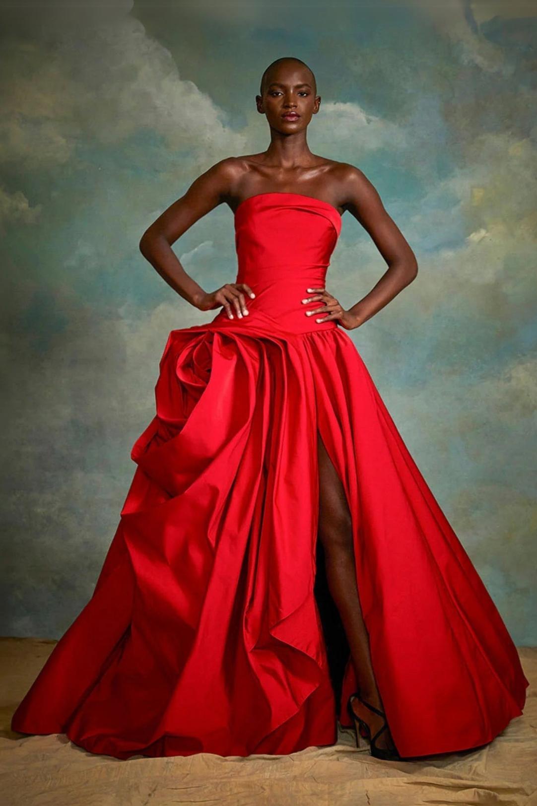 Red strapless gown with a hand-draped rose detail, side slit, and luxurious fabric for a formal silhouette.
