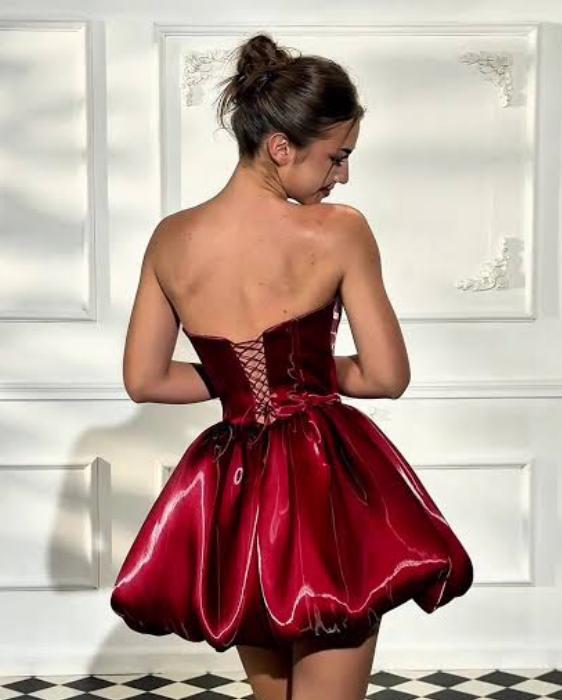 Strapless burgundy liquid satin mini dress with a corseted back and voluminous architectural skirt.