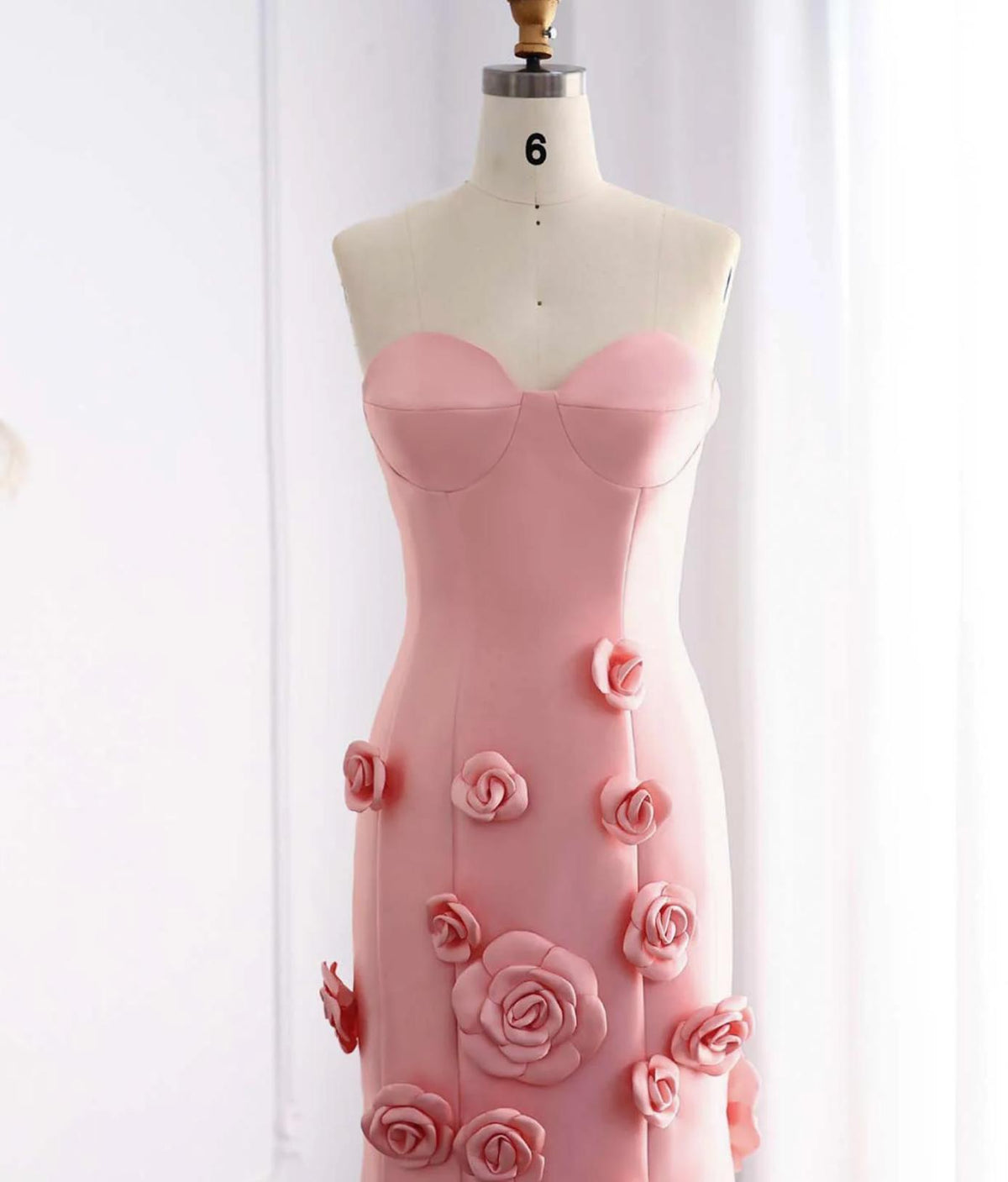 Pink satin mermaid gown with a sweetheart neckline and cascading 3D floral appliqués on a mannequin.
