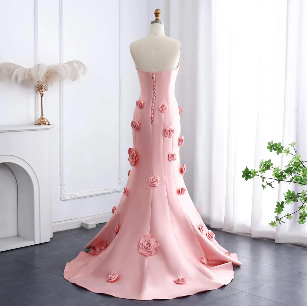 Back view of a pink satin mermaid gown with 3D floral appliqués, a sweetheart neckline, and a lace-up corset back.