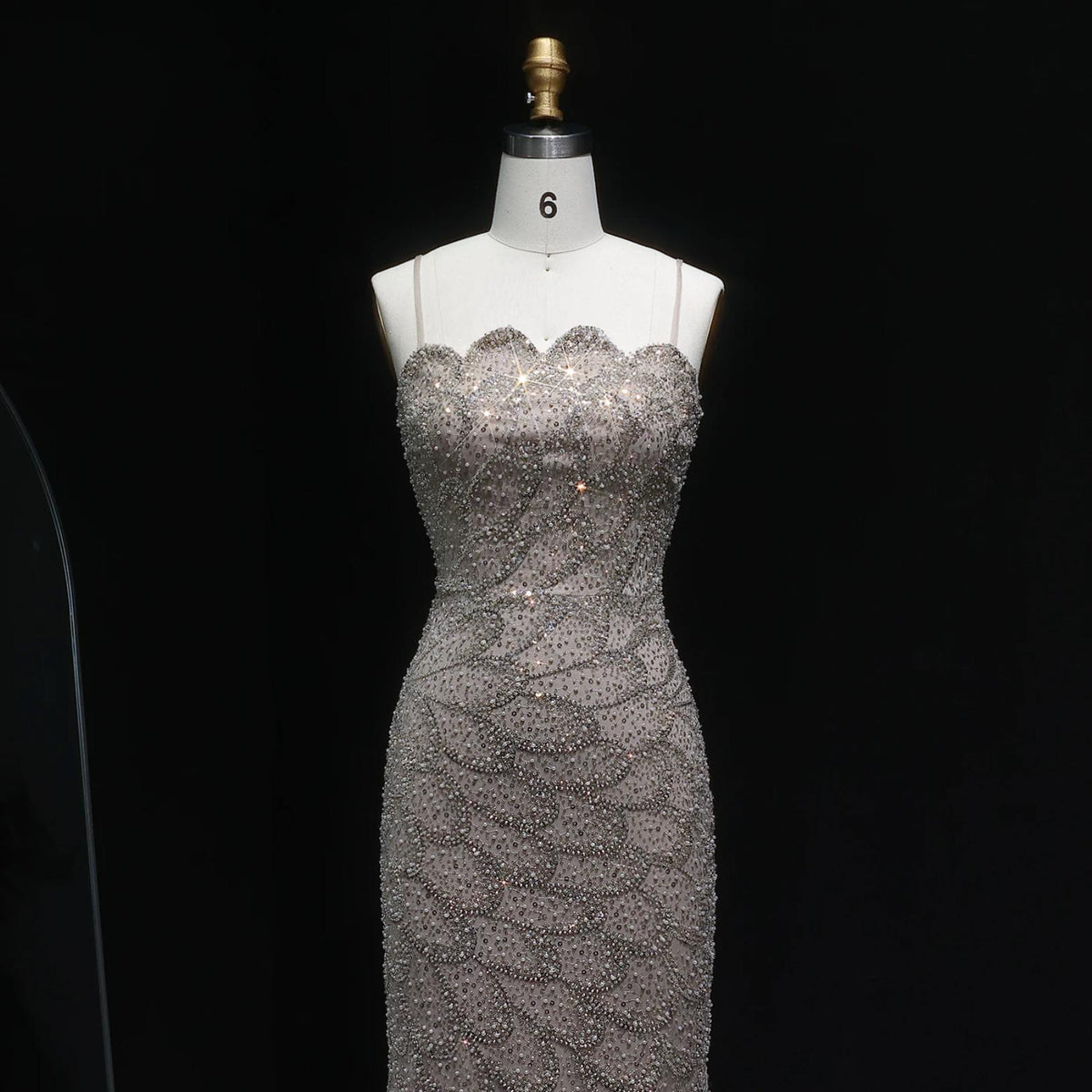 Emerald green strapless mermaid gown with intricate crystal beading and tulle detailing on a mannequin.