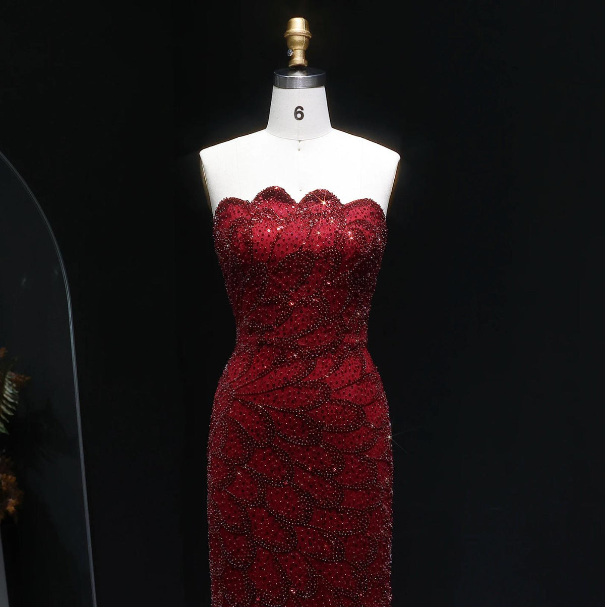 Strapless deep red mermaid gown featuring intricate crystal beading and scalloped neckline on a size 6 mannequin.