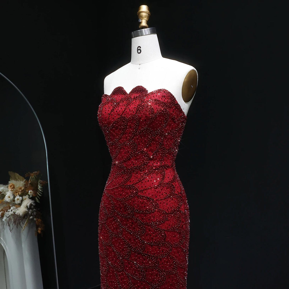 Strapless red mermaid gown featuring intricate crystal beadwork and scalloped bodice details on a size 6 mannequin.