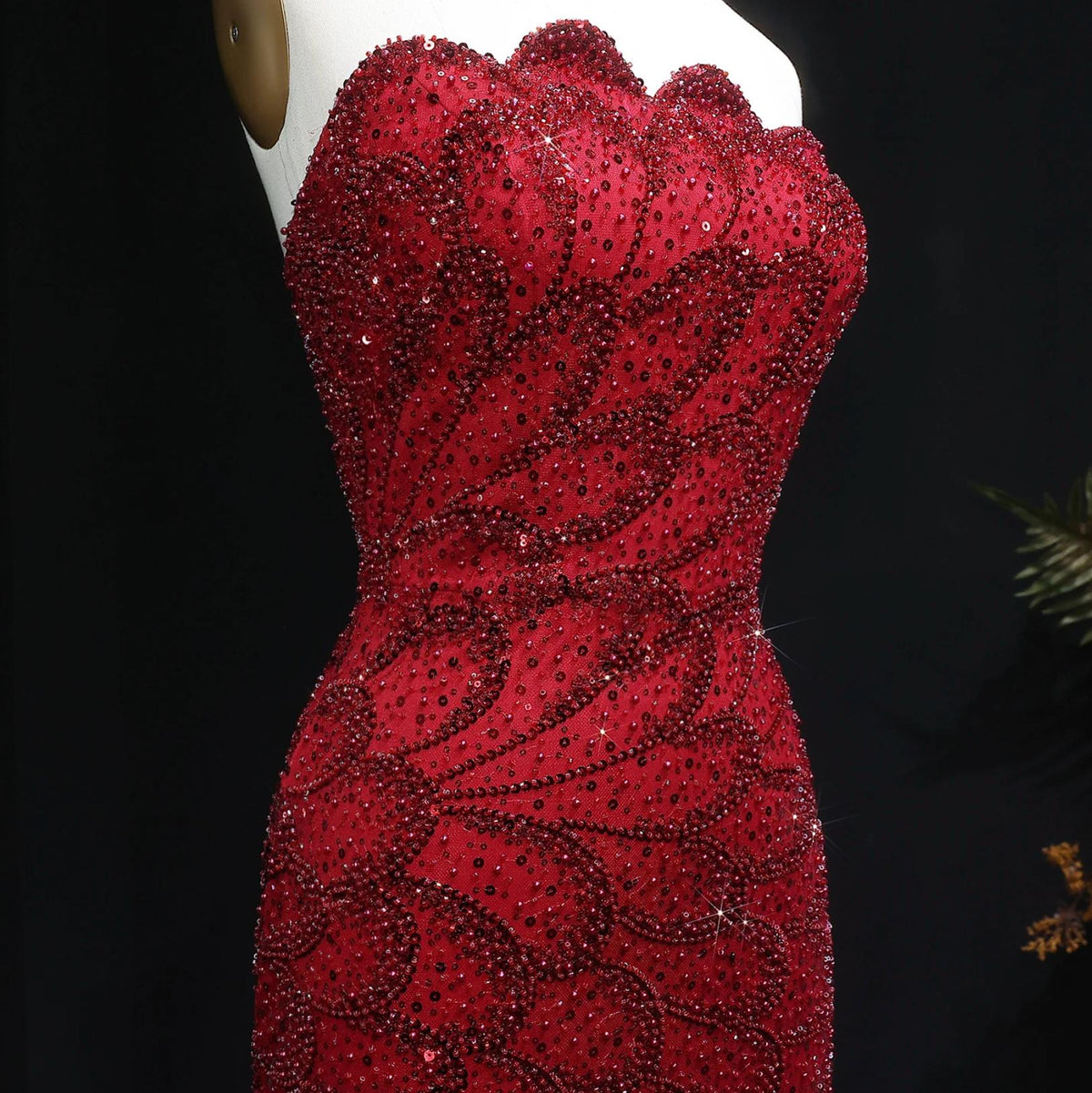 Strapless red mermaid gown featuring intricate beaded patterns and sparkling crystal appliqués on a tulle base.