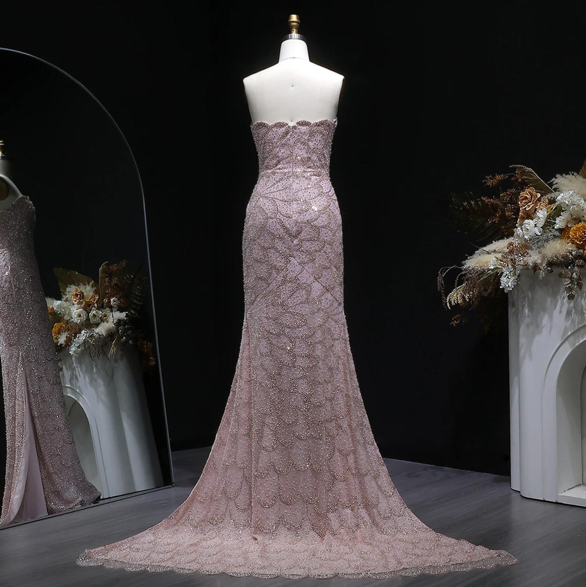 Strapless blush pink mermaid gown with intricate crystal beading, tulle fabric, and a sweeping train on a mannequin.