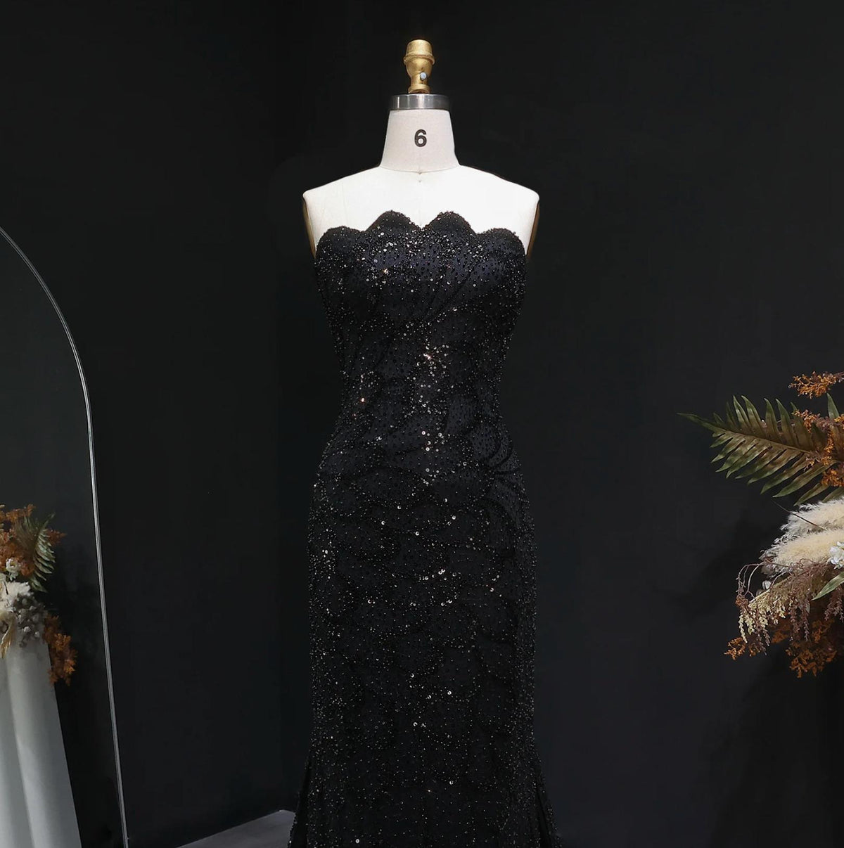 Strapless black mermaid gown featuring intricate beading and crystal appliqués on a mannequin.